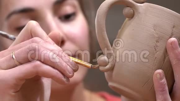 女陶工的特写强调细节使用流苏在她手中的生泥杯视频的预览图