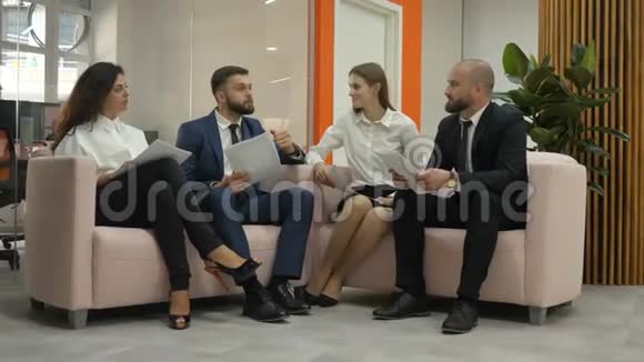 两个女人和两个男人坐在办公室里其中一个男人解释了文件的本质视频的预览图
