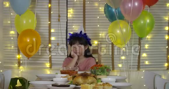 悲伤的亚洲小女孩独自在一张桌子上庆祝她的生日桌子上有一个蛋糕和一支蜡烛动作缓慢视频的预览图