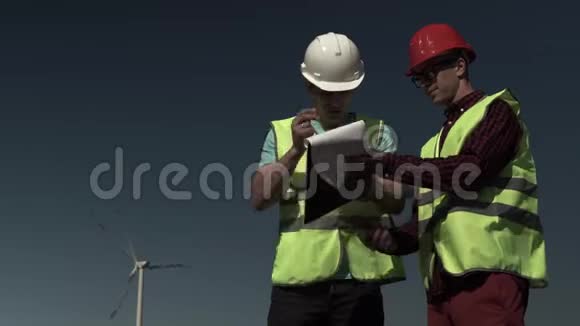 两名青年工程师男子走近风车视频的预览图
