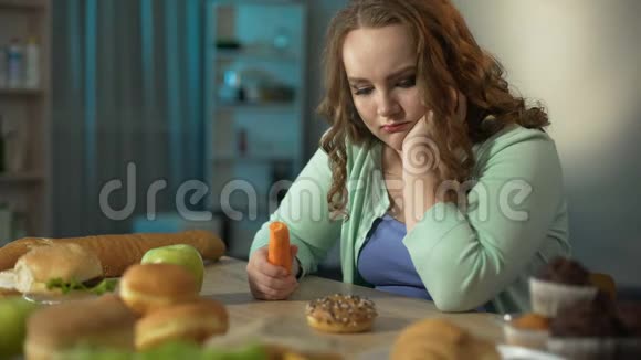 超重女孩看着甜甜圈手里拿着胡萝卜健康饮食视频的预览图