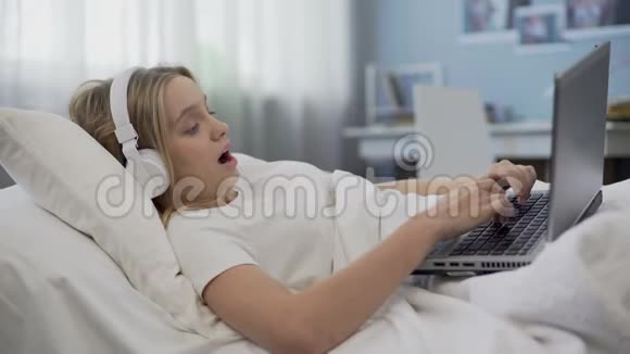 微笑的女孩躺在床上用笔记本电脑在社交媒体上与朋友交流视频的预览图