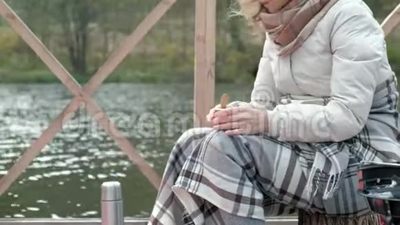 一位穿着温暖衣服的女游客拿着背包在河岸边的桥上藏了一条毯子一只狗在附近跑视频的预览图