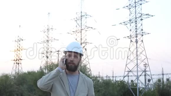 站技术负责人戴着白色安全帽站在电站附近与工人通电话视频的预览图