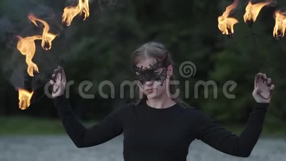 戴着面具的年轻美女在树前用火焰表演节目的肖像有技巧的消防艺术家视频的预览图