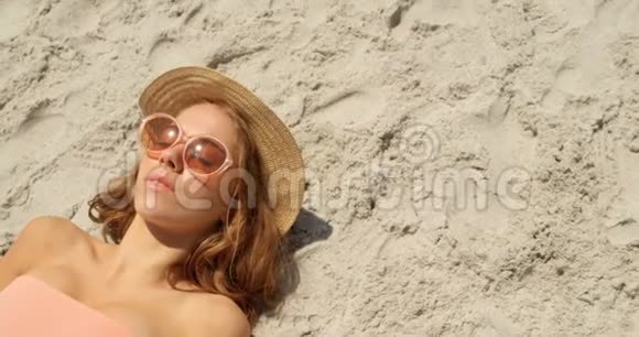 高角度视角下戴帽子的白人女性在海滩上放松4k视频的预览图
