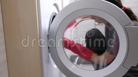 戴红色橡胶手套的女人正在用海绵洗洗衣机视频的预览图