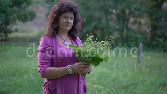 一位老年妇女手里拿着一束野花和草地看着一团在花束上方旋转的视频的预览图