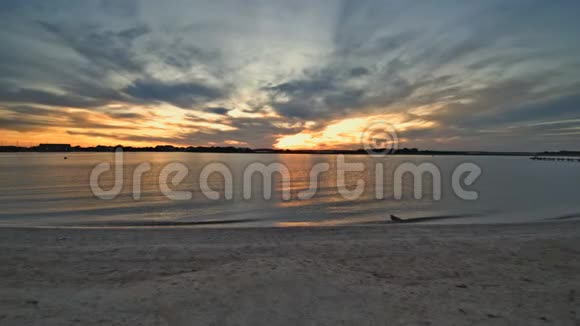 空中无人驾驶飞机在夕阳的天空下在浅沙的海面上飞行视频的预览图