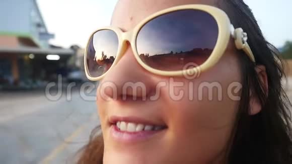 戴着太阳镜的年轻快乐女人骑着摩托车在热带岛屿的道路上慢动作靠近她的脸视频的预览图