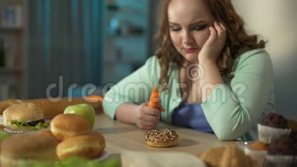 胖乎乎的小女孩几乎要为桌上的甜甜圈哭泣强迫自己吃胡萝卜视频的预览图