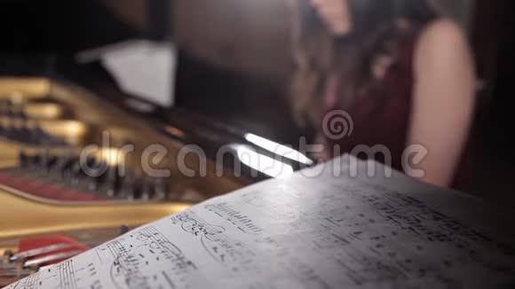 女孩坐在钢琴旁学习音乐音符音乐表演还有笔记视频的预览图