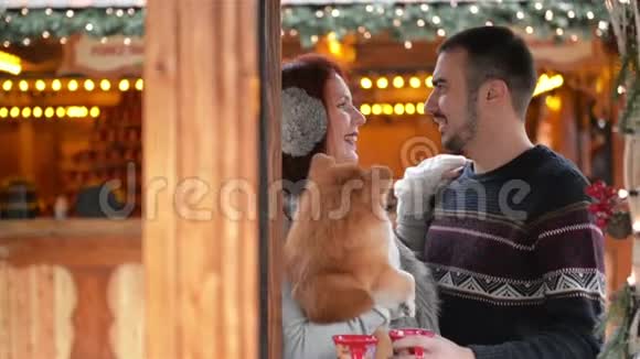 有几个情人和一只可爱的狗抱在一起他们在一起心情很好穿着的病房身后的圣诞灯视频的预览图