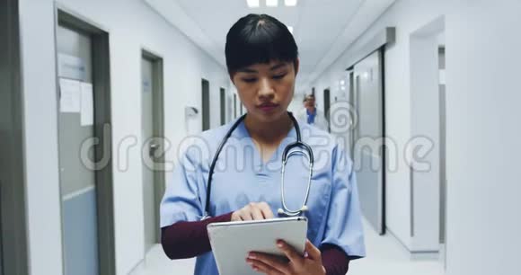 女医生使用4k平板电脑站在医院走廊视频的预览图