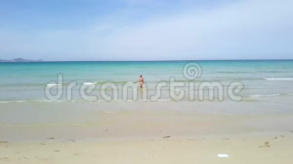 年轻女子穿着比基尼在蓝色的海洋天际线背景在天堂海滩上的绿松石海中的无人机观看女人视频的预览图
