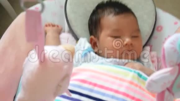 可爱的亚洲婴儿感到困倦躺在秋千摇篮里视频的预览图