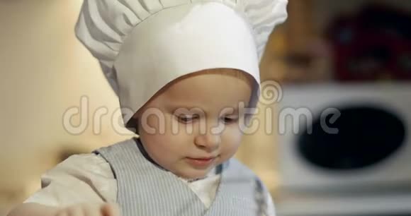 一个穿着烹饪帽的快乐男孩和一个金属平底锅和推杆玩视频的预览图