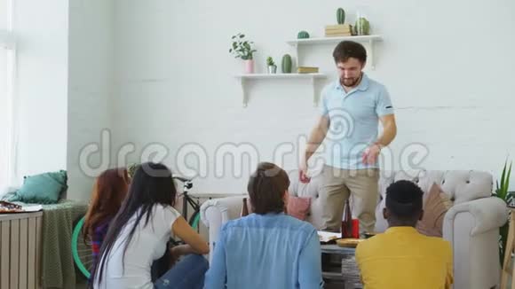 一群朋友在家玩派对游戏玩得很开心年轻人展示某物或某人他的室友在尝试视频的预览图
