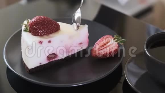 女孩在黑玻璃桌上吃奶油水果蛋糕蛋糕和一杯黑咖啡视频的预览图