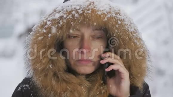 站在雪下的女人用手机打电话和上网视频的预览图