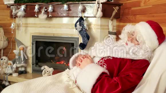 睡觉的sanaclaus劳累的老圣诞老人在辛苦工作后打盹闲暇时间房间有壁炉视频的预览图