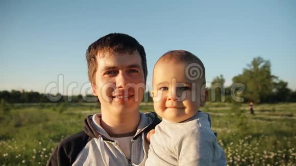 日落时一个年轻快乐的父亲和孩子在花田里的缓慢动作视频的预览图
