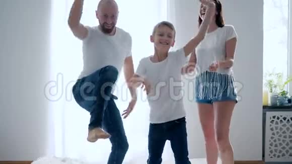 和父母在一起的男孩在玩耍在床上跳跃动作缓慢有趣的时刻视频的预览图