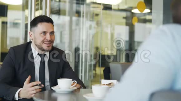 在与莫德咖啡馆的合伙人交谈时一位虔诚的高加索商人一边打手势一边为自己的利润感到高兴视频的预览图