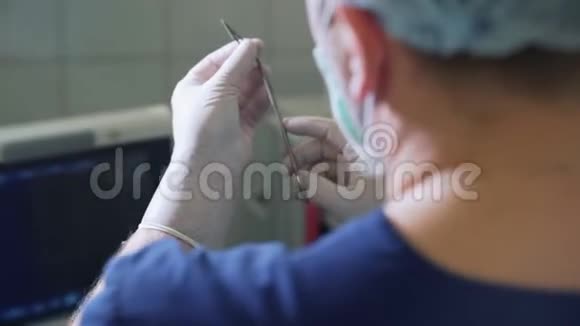 个人视角医生戴无菌手套将手术刀刀片握在手术前夹钳中POV关闭视频的预览图