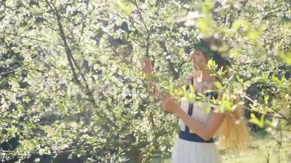 年轻漂亮的女人闻着开花的树视频的预览图