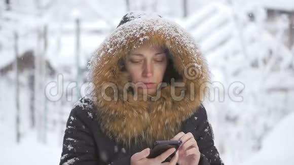 站在雪下的女人用手机打电话和上网视频的预览图