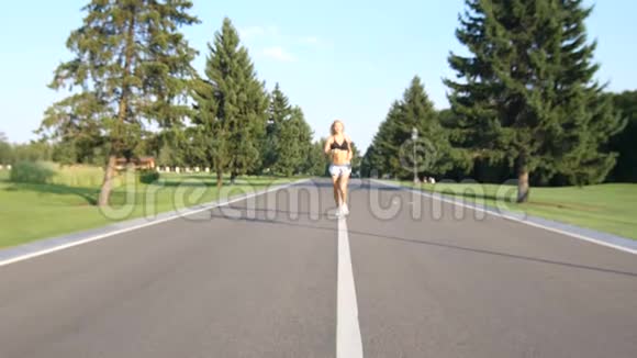 一条美丽健康的金发女郎在夏日阳光下沿着郊区的街道奔跑视频的预览图