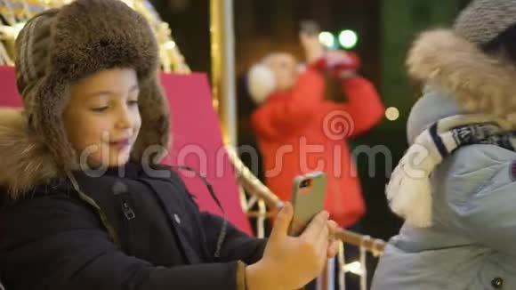 两个男孩在圣诞树附近的广场上自拍视频的预览图