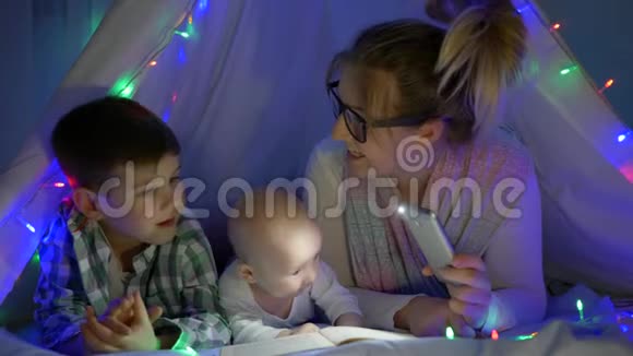 为人父母母亲为小儿子读书用手电筒拿着手机视频的预览图