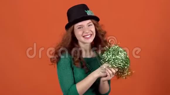 一位年轻女子在橘色的墙上戴着一顶帽子手里拿着一个绒球庆祝圣帕特里克节视频的预览图