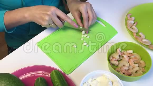 女人切蒜桌子上的下一个是虾豆腐块和烹饪用的蔬菜视频的预览图