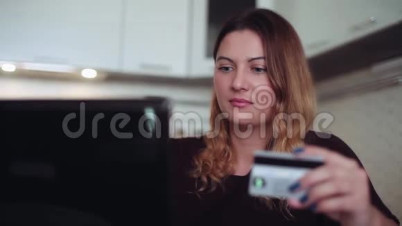一个穿深色衣服的漂亮年轻女人用信用卡和电脑买礼物家庭风格视频的预览图