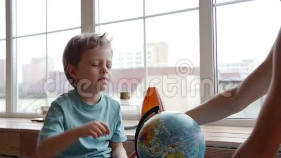一位富有魅力的白种人母亲用地球仪向她年轻的儿子展示世界各国视频的预览图