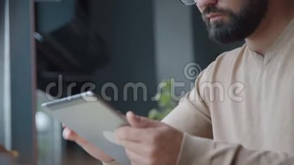 长胡子的人用平板电脑看新闻滚动页面皱眉视频的预览图