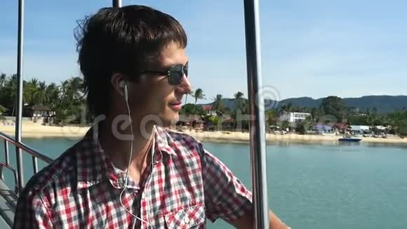 一个戴着耳机的太阳镜的帅哥在游轮上旅行时听音乐慢动作1920x1080视频的预览图