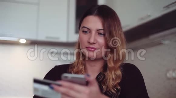 网上购物一个漂亮的年轻女孩使用信用卡和智能手机进行在线购买高清高清视频的预览图