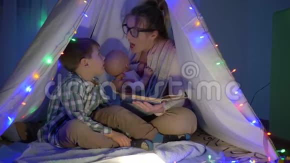 幸福的家庭妈妈晚上给坐在wigwam的儿子读童话视频的预览图