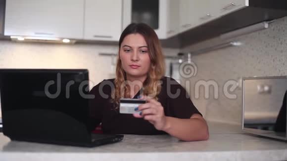一位漂亮的年轻女子用笔记本电脑和碎卡在网上购物家庭风格视频的预览图