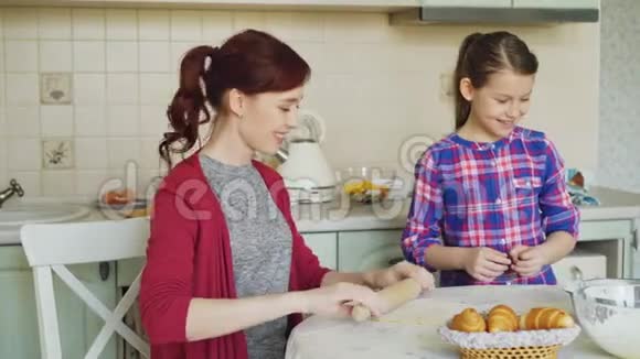 年轻的妈妈在周末在厨房做饭周末在厨房做饭时和小可爱的女儿说话家庭食物视频的预览图