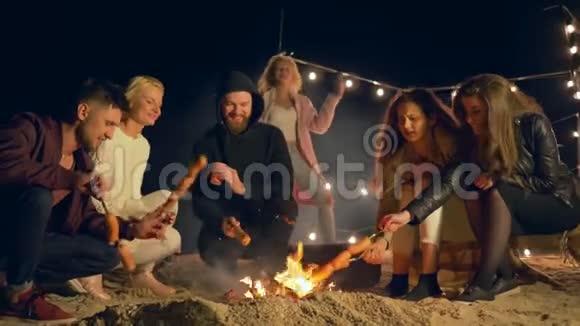 年轻人在户外度假时一边在火上烧香肠一边跳舞视频的预览图