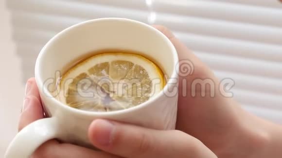 在女孩的手心里放着一杯柠檬茶秋季维生素茶预防感冒视频的预览图