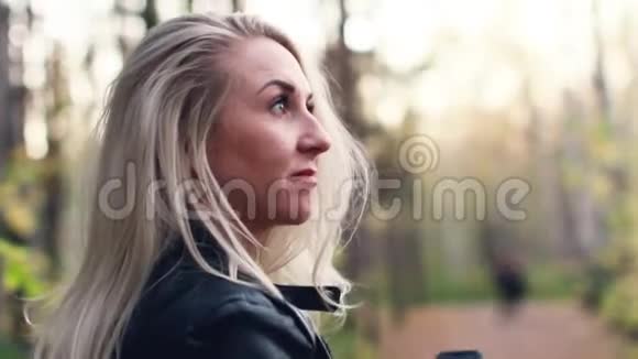 秋天公园散步的年轻迷人金发女郎的肖像视频的预览图