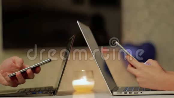 一对学生手在笔记本电脑附近的智能手机上工作视频的预览图