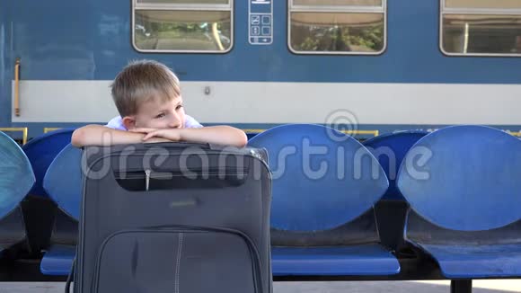 一个带大行李的单身孩子坐在火车站久等好东西就要来了视频的预览图