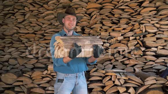 一个男人戴着牛仔帽在仓库里拿着一堆木柴的画像视频的预览图